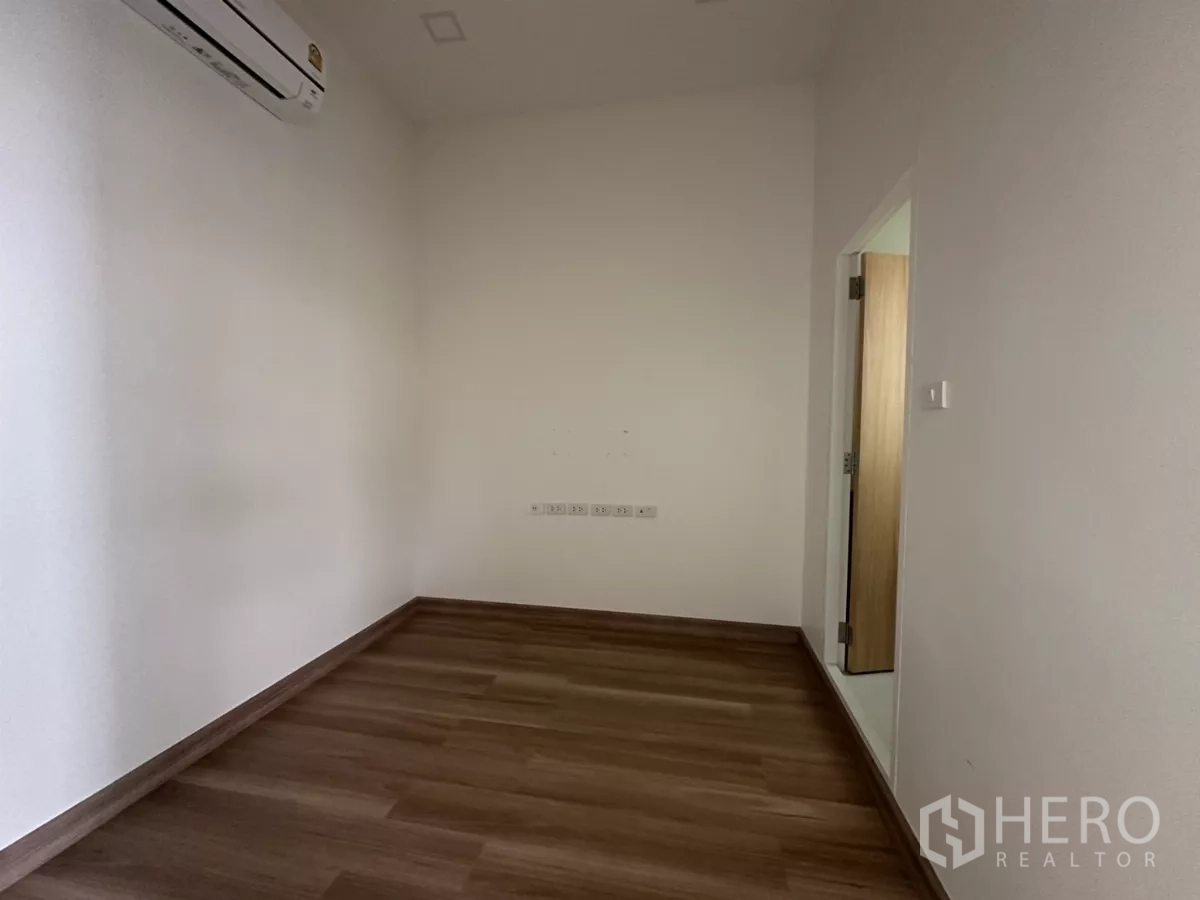 Retail Space for rent in Phra Khanong, Bangkok - Minimal room with wood flooring, split‑type AC and doorway to ancillary space.