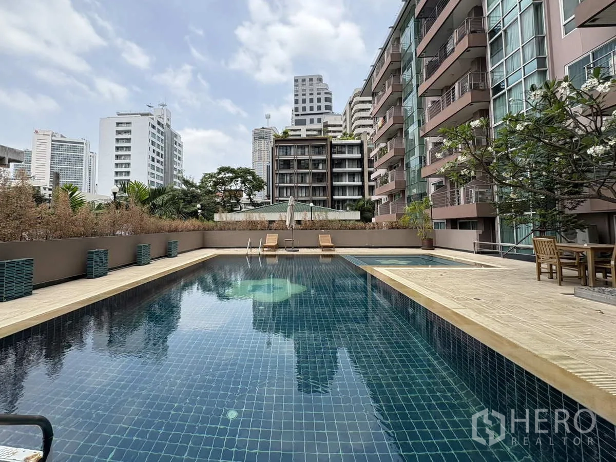 Condominium for rent in Khlong Toei, Bangkok - Outdoor swimming pool surrounded by mid‑rise buildings and seating areas.