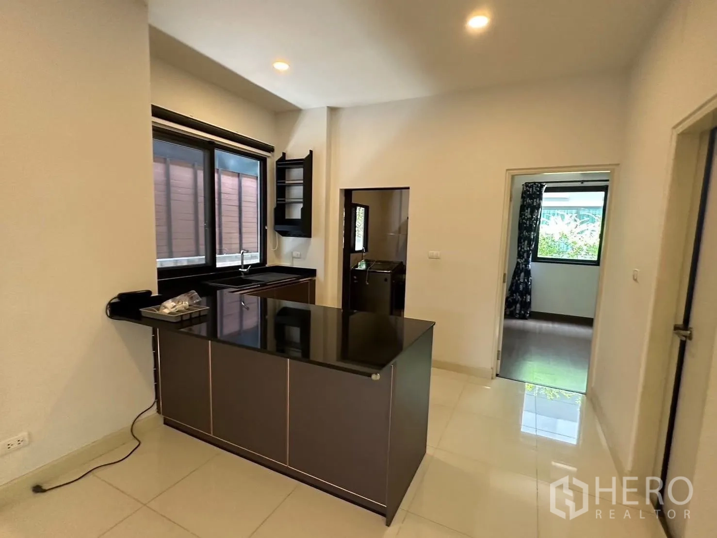 Detached House for rent in Bang Phli, Samut Prakan - View of the kitchen peninsula and an adjoining room with large windows.