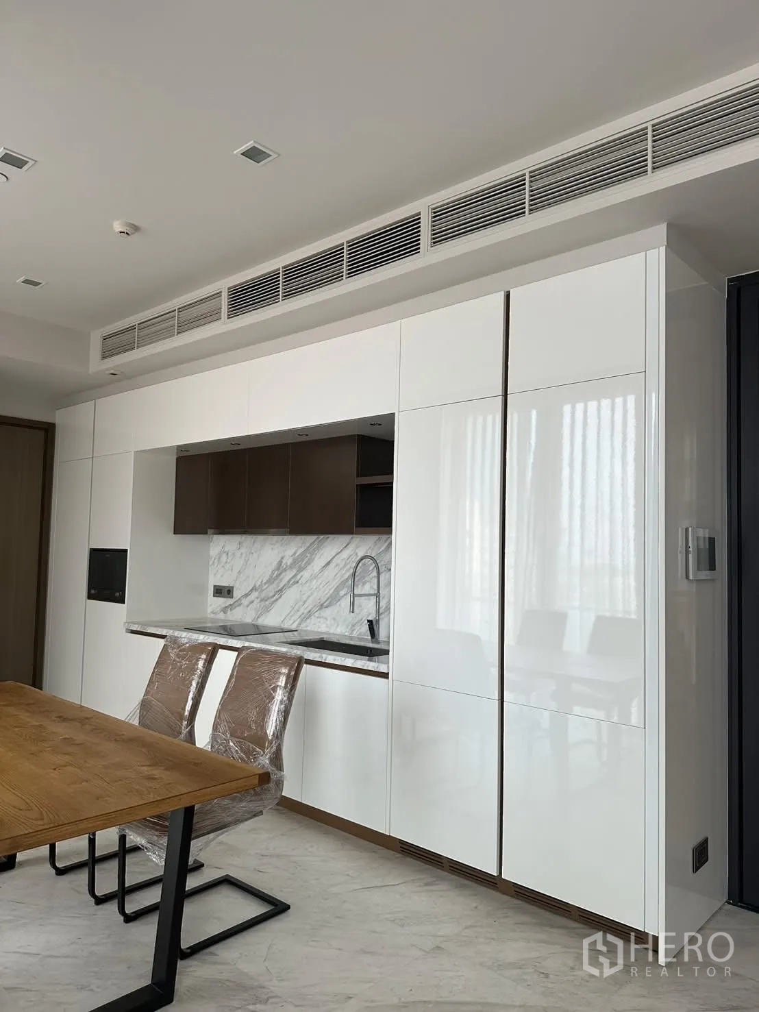 คอนโด for rent or sale in Watthana, Bangkok - ครัวแพนทรีสมัยใหม่ตู้บานเงาสีขาวและผนังกันเปื้อนลายหินอ่อน.