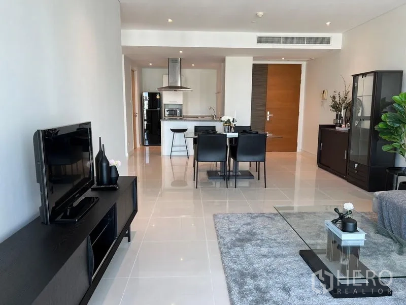 Condominium for rent in Watthana, Bangkok - Spacious open-plan lounge with glossy tile floors, TV console, dining set, and a kitchen island beyond.