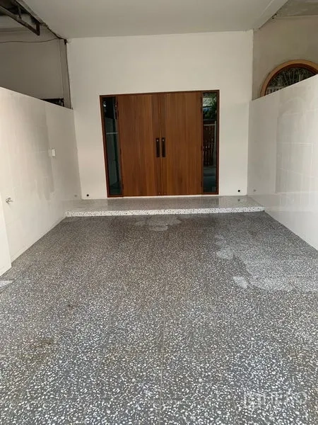 Townhouse for sale in Yan Nawa, Bangkok - Covered carport with terrazzo flooring and wooden sliding entry doors.