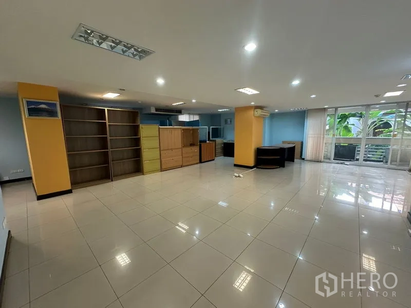 Office Space for sale - Open-plan office with shelving units, desks and sliding doors to greenery.