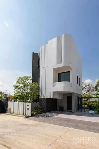 独立式住宅 出租或出售在Lat Krabang, Bangkok - 曼谷拉甲邦现代三层独栋住宅外观，白色立面与车道。