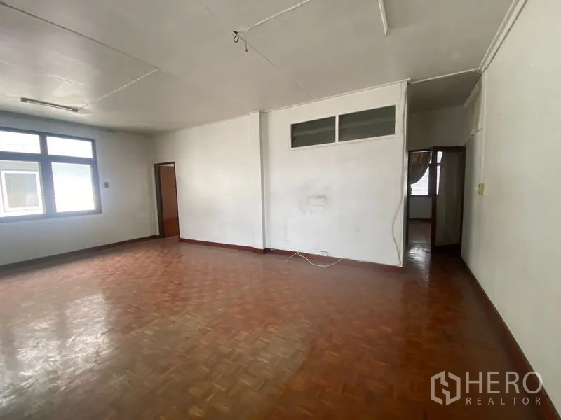Home Office for rent in Khlong Toei, Bangkok - Open-plan room with parquet floor, white walls, and multiple doorways.