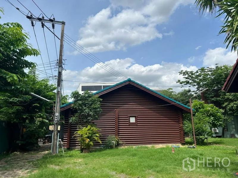 สำนักงานที่บ้าน ให้เช่าในSuan Luang, Bangkok - ด้านข้างอาคารไม้พร้อมสนามหญ้า ต้นไม้ และเสาไฟฟ้า