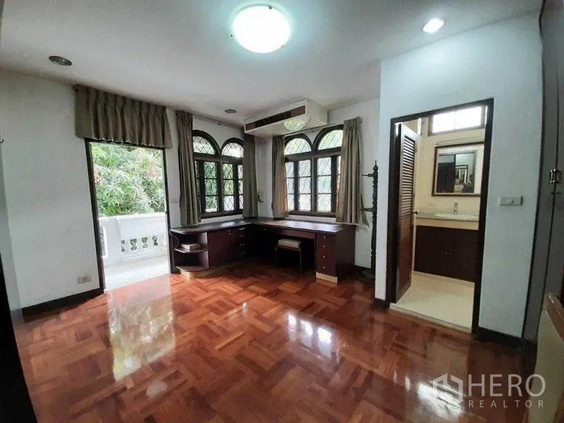 Detached House for rent in Watthana, Bangkok - Bedroom with corner work desk, access to balcony and door to ensuite bathroom.
