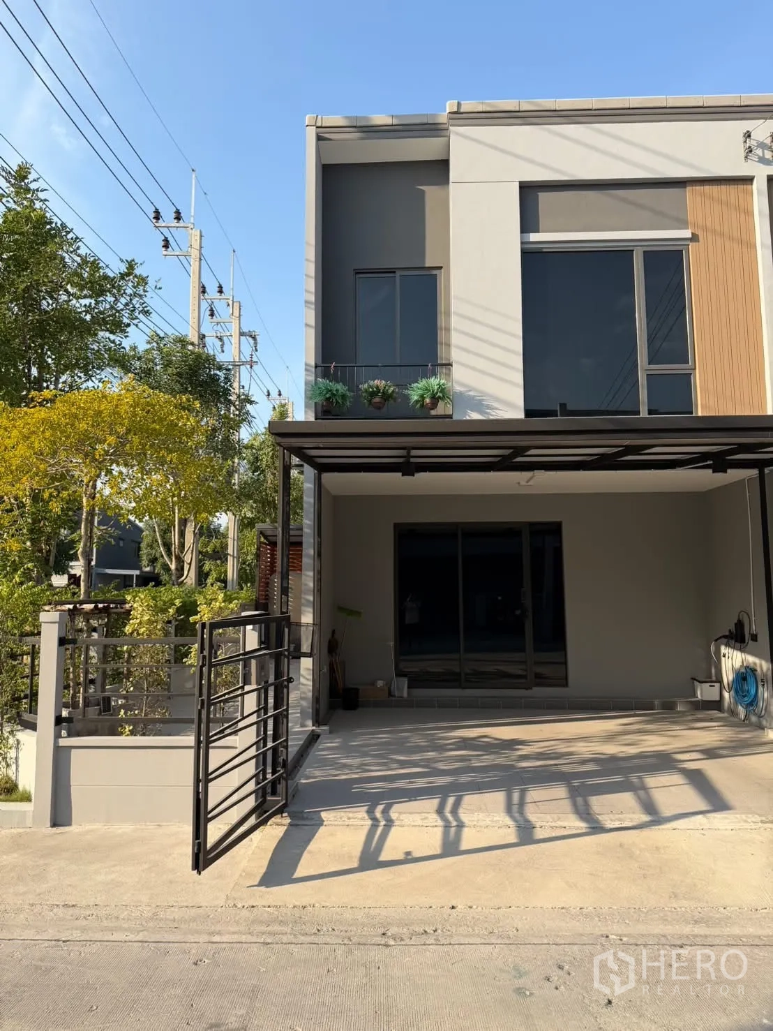 ทาวน์เฮาส์ for rent in Bang Phli, Samut Prakan - ด้านหน้าทาวน์เฮ้าส์สมัยใหม่ มีกันสาดที่จอดรถและระเบียงแขวนต้นไม้
