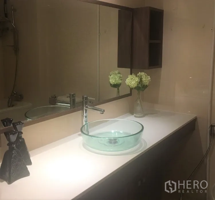 公寓 出租在Watthana, Bangkok - 现代浴室洗手台，玻璃台盆、长镜与壁柜。