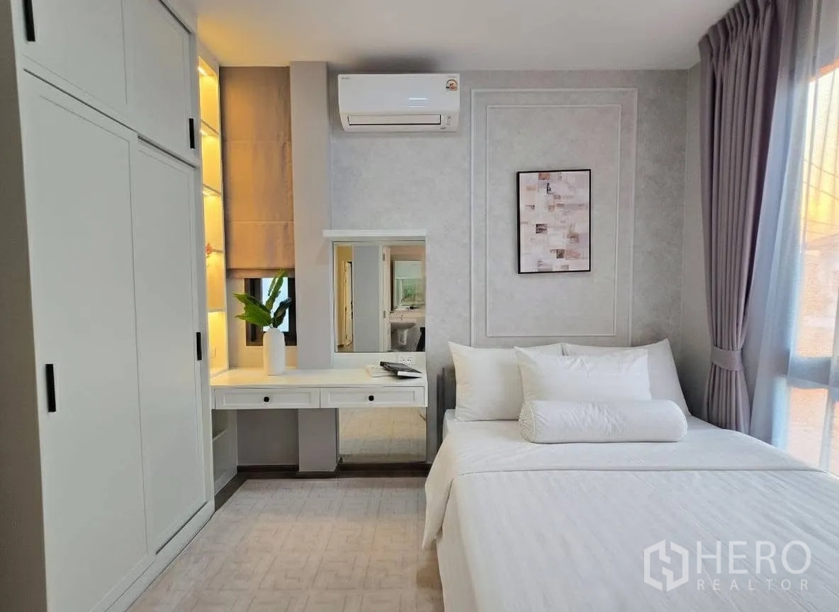 บ้าน for rent or sale in Bang Phli, Samut Prakan - มุมห้องนอนเห็นเตียง โต๊ะแต่งหน้าพร้อมกระจก และตู้บานเลื่อนโทนเทา