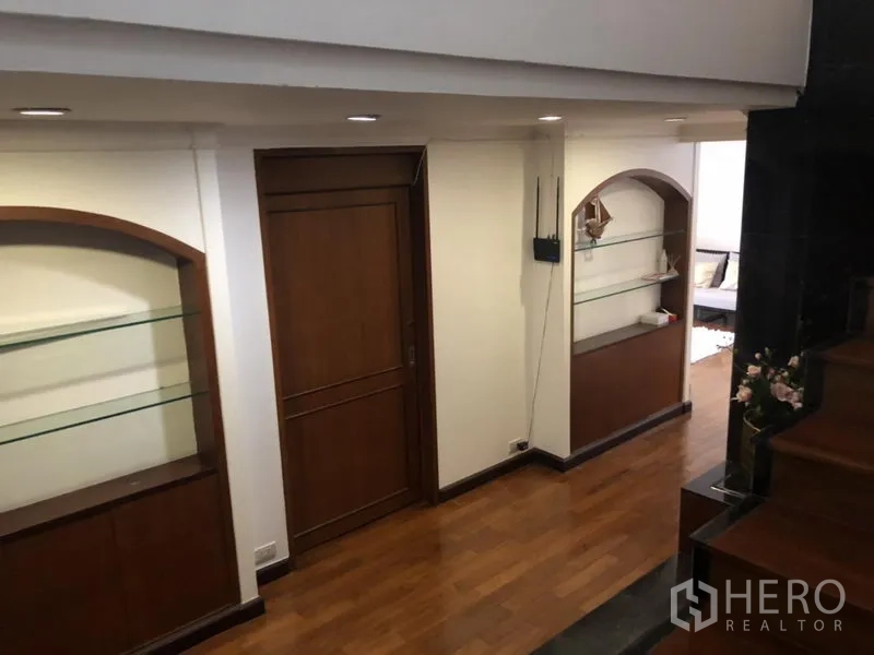 Condominium for sale in Watthana, Bangkok - Landing with arched built-in glass display shelves and wooden doors.