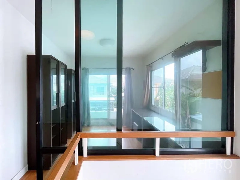 บ้าน ให้เช่าในBang Na, Bangkok - โถงชั้นบนสว่างด้วยผนังกระจกสูงจรดเพดานและหน้าต่างเปิดสู่ระเบียง