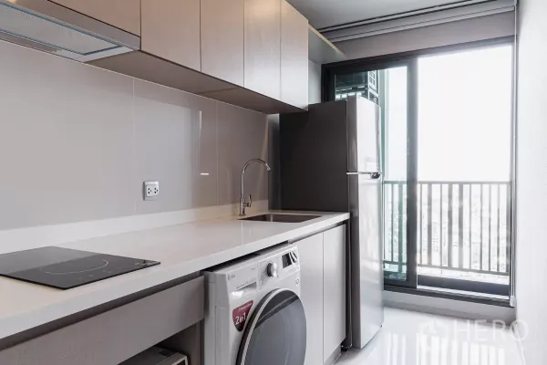Condominium for rent in Chatuchak, Bangkok - Separate kitchen with induction hob, sink, LG washer-dryer and balcony access.
