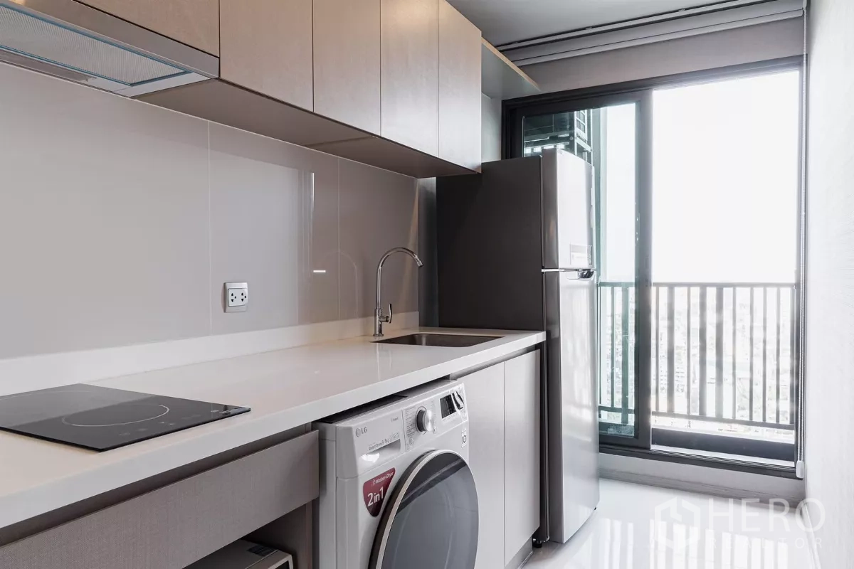 Condominium for rent in Chatuchak, Bangkok - Separate kitchen with induction hob, sink, LG washer-dryer and balcony access.