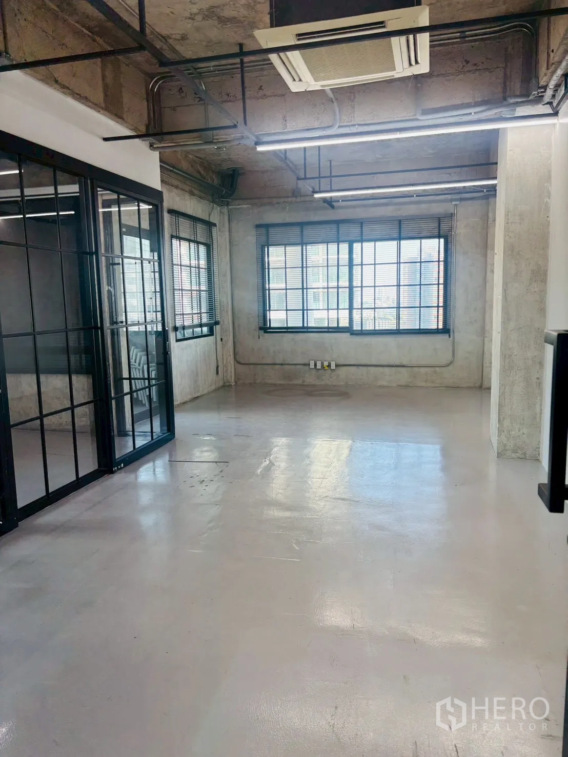 Office Space for rent in Khlong Toei, Bangkok - Industrial-style office interior with exposed ceiling, LED strip lights, polished floor and black-framed glass meeting room.