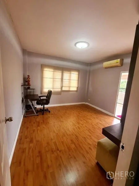 Detached House for rent in Sai Mai, Bangkok - Spacious room with wood flooring, desk, window blinds and a wall-mounted air conditioner.