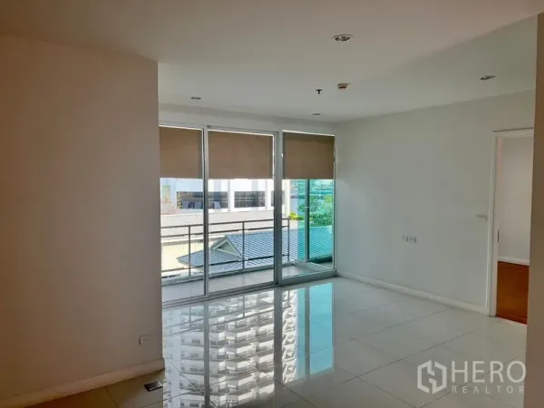 Condominium for rent in Bang Kho Laem, Bangkok - Bright living area with glossy tile floors and floor-to-ceiling sliding glass doors opening to a balcony with city views.