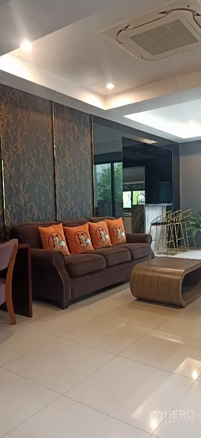 Detached House for rent or sale in Khan Na Yao, Bangkok - Modern lounge with recessed ceiling lights, tiled floor and sofa set facing large windows.