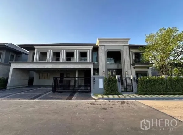 บ้าน ให้เช่าในLat Krabang, Bangkok - ด้านหน้าบ้านเดี่ยวหรู โรงจอดรถมีหลังคา และประตูรั้วสีดำ