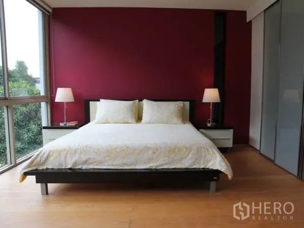 Condominium for rent in Khlong Toei, Bangkok - Master bedroom with red accent wall, corner windows and bedside lamps.
