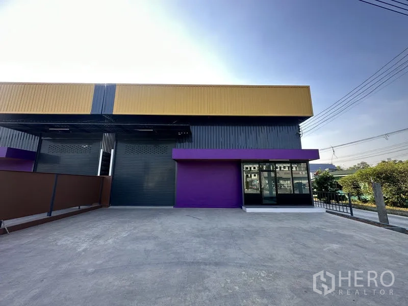 货栈 出租在Lam Luk Ka, Pathum Thani - 灰黄配色仓库前的开阔混凝土前院，适合卡车装卸。