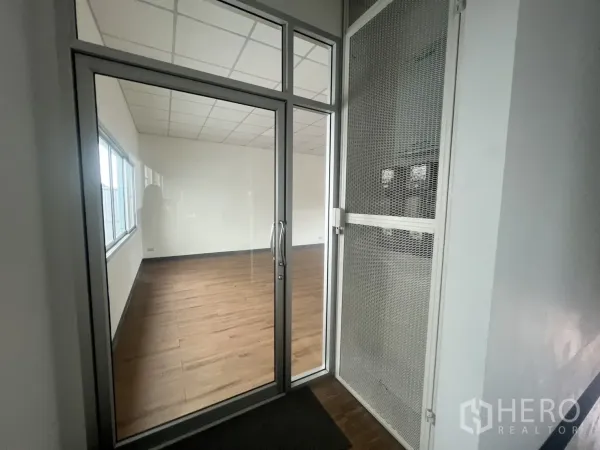 Retail Space for rent - Glass entry door with security screen opening to a bright retail room with wood flooring.