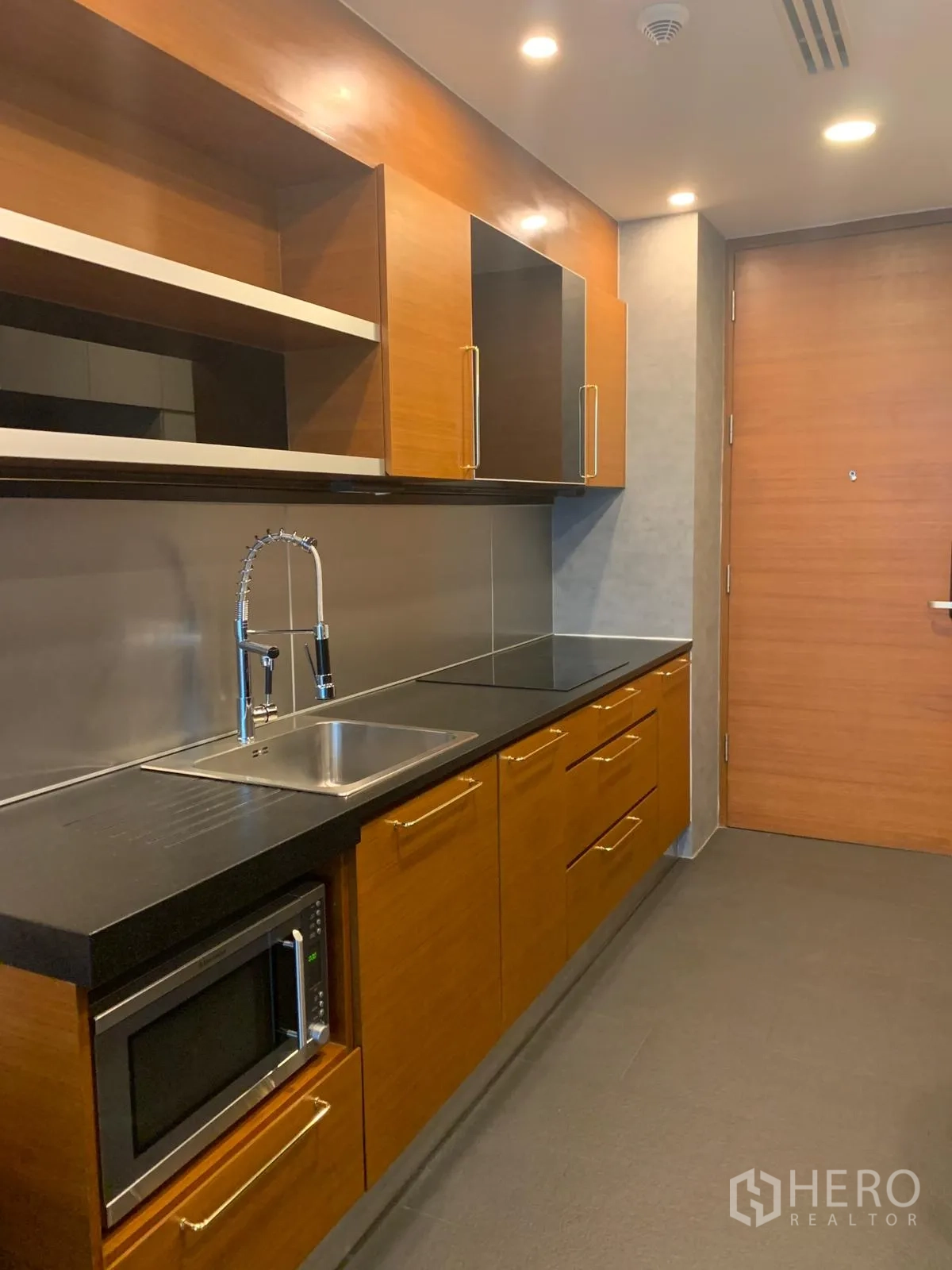 Condominium for sale in Khlong Toei, Bangkok - Close‑up of kitchen cabinetry with sink, cooktop and built‑in microwave.