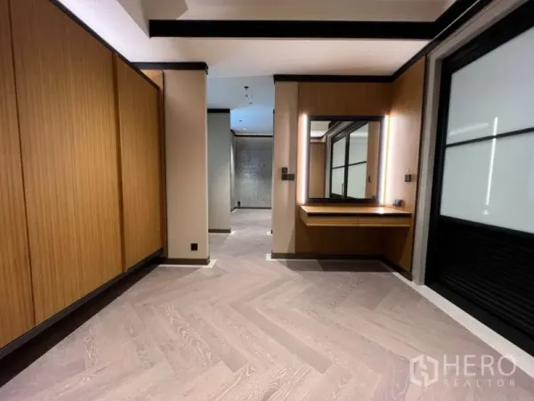 Condominium for rent in Sathon, Bangkok - Bedroom dressing area with built-in wood wardrobes and a lighted vanity.