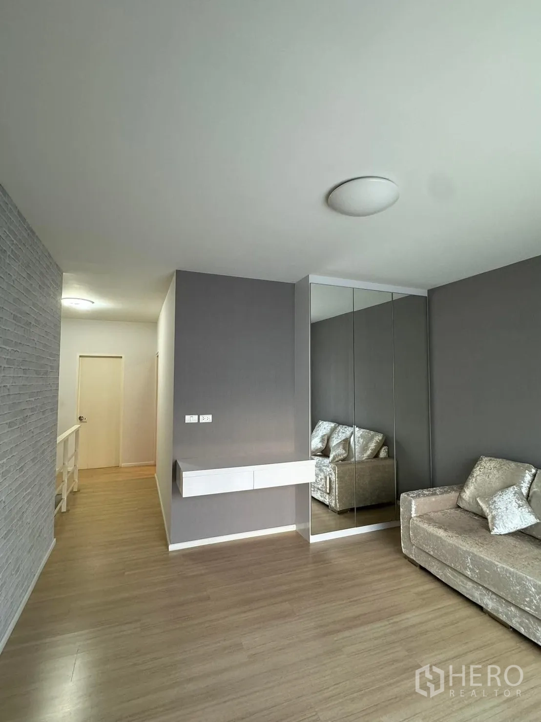 Townhouse for rent in Suan Luang, Bangkok - Upper-floor lounge with floating shelf, mirrored closet and gray accent walls.