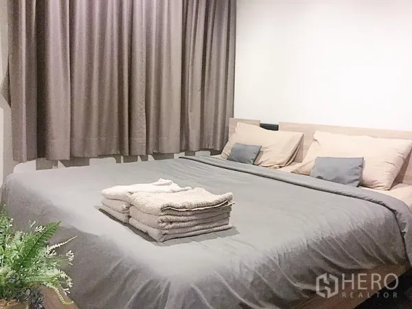 คอนโด ให้เช่าในWatthana, Bangkok - ห้องนอนอบอุ่น ปูผ้าปูเตียงสีเทา หมอนหลายใบ และผ้าม่านทึบแสงเต็มบาน