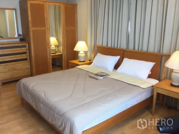 Condominium for rent in Khlong Toei, Bangkok - Master bedroom with king bed, bedside lamps and matching wooden wardrobes.