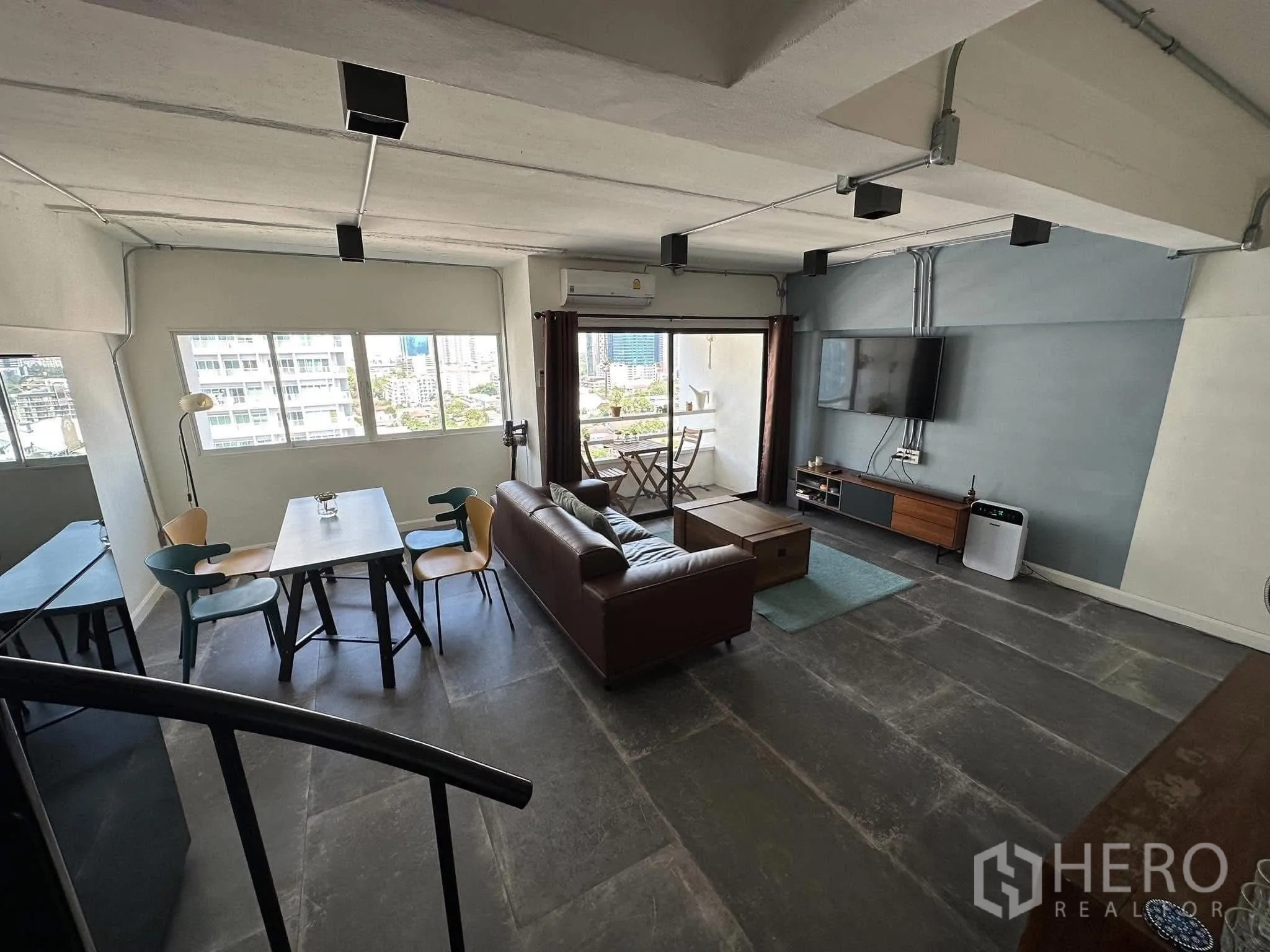 公寓 出租在Watthana, Bangkok - 宽敞的复式客厅，配沙发、餐桌与可眺望曼谷天际线的阳台。