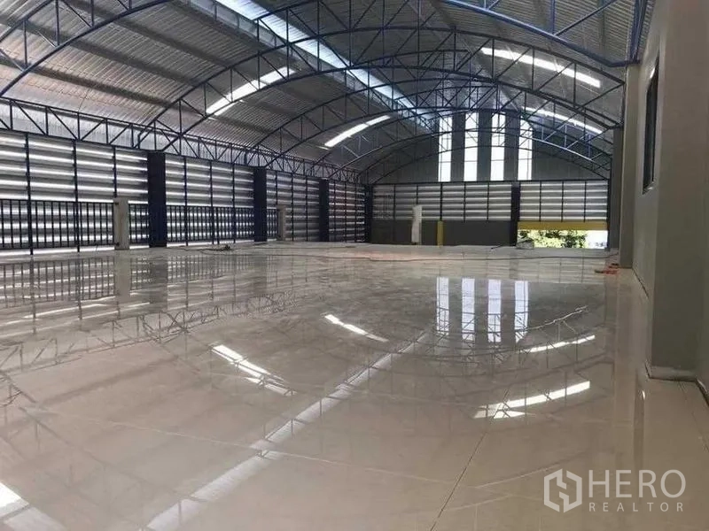 货栈 出租在Bang Pakong, Chachoengsao - 宽阔仓库地面，亮面瓷砖，高跨钢桁架屋顶与卷帘门。