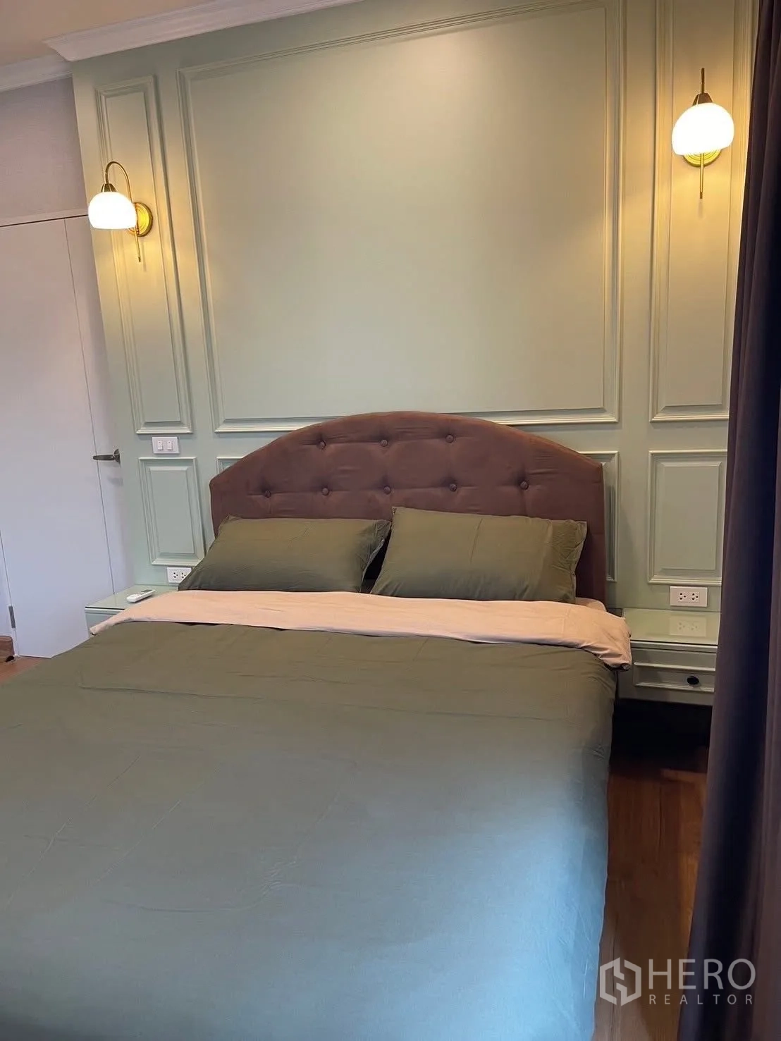 Detached House for rent in Bang Phli, Samut Prakan - Bedroom with green paneled wall, padded headboard and warm wall sconces.