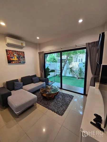 独立式住宅 出租在Bang Phli, Samut Prakan - 客厅另一角度，沙发地毯与草坪景观
