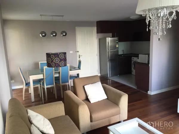 Condominium for rent in Watthana, Bangkok - Open-plan living and dining area beside a compact kitchen with stainless fridge.