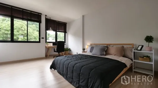 Townhouse for rent in Huai Khwang, Bangkok - Spacious bedroom with desk, big windows, wood floors and green tree views.