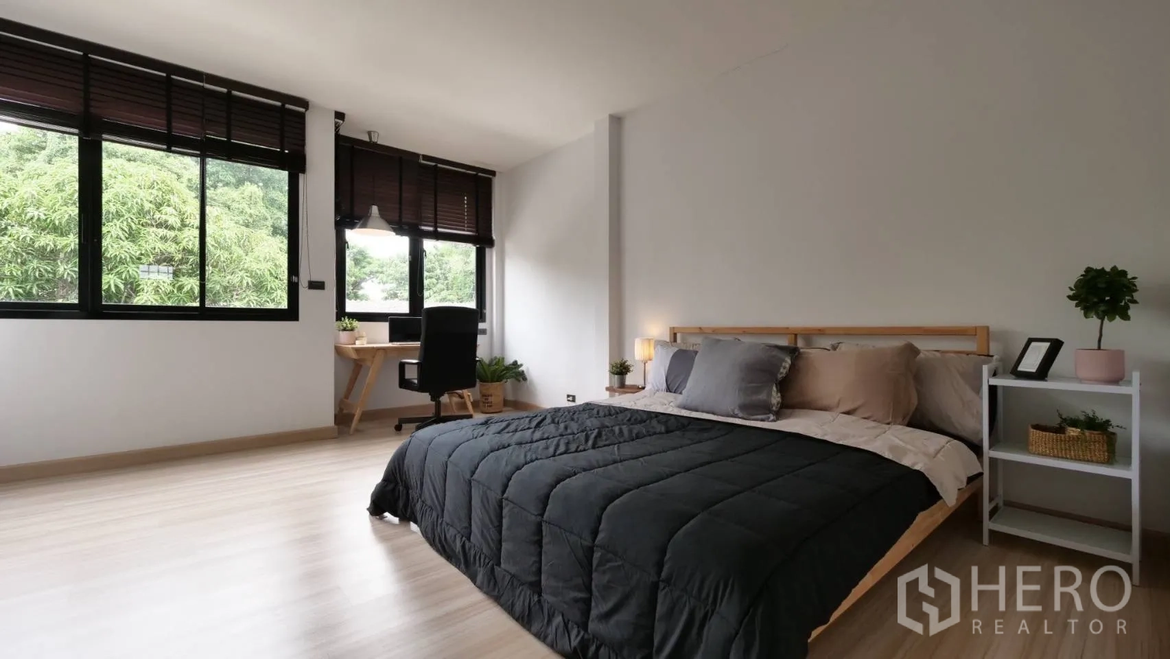 Townhouse for rent in Huai Khwang, Bangkok - Spacious bedroom with desk, big windows, wood floors and green tree views.