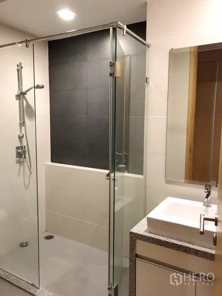 Condominium for rent in Khlong Toei, Bangkok - Contemporary bathroom featuring glass-enclosed shower and square basin vanity.