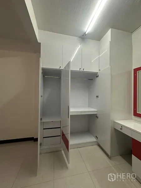 Shophouse for rent or sale in Phra Khanong, Bangkok - Built-in white wardrobes with open cabinets and a dressing counter in a bright room.