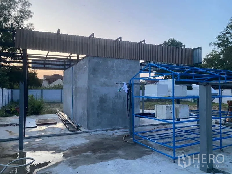 货栈 出租或出售在Nong Chok, Bangkok - 仓库旁室外公用区，混凝土设备房与金属货架结构。