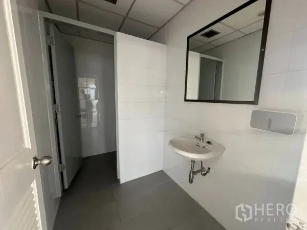 Office Space for rent in Bang Rak, Bangkok - Clean tiled restroom inside the office with wall-mounted sink, mirror, and private cubicle.
