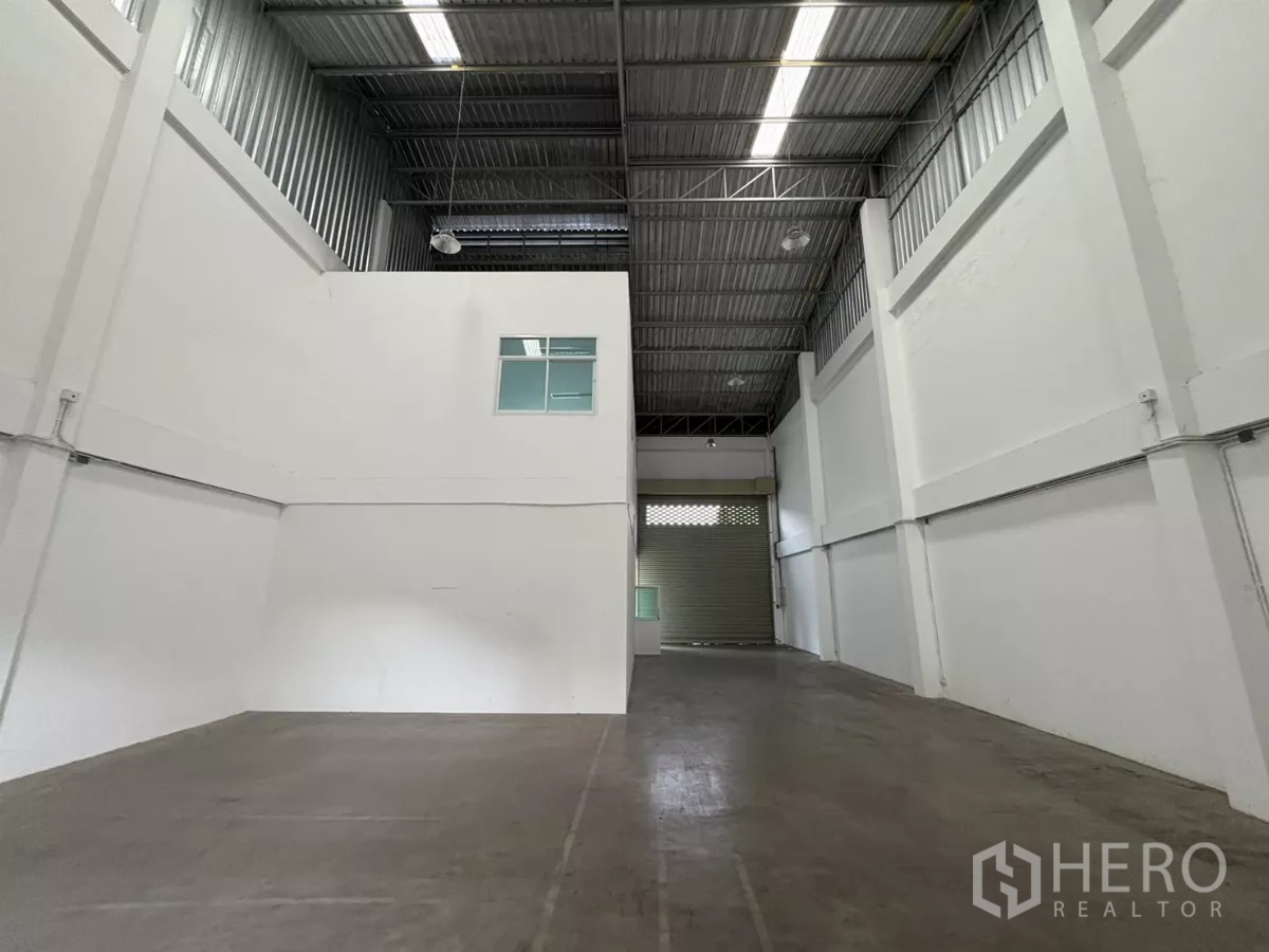 Factory for rent in Phra Samut Chedi, Samut Prakan - Spacious production bay facing a large roller shutter door.
