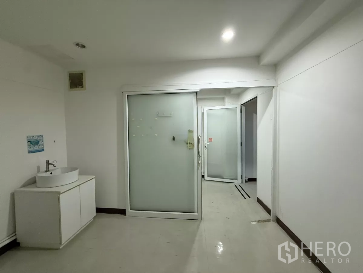 办公空间 出租在Din Daeng, Bangkok - 走廊式工作区，磨砂玻璃门、白色柜体与明亮照明。