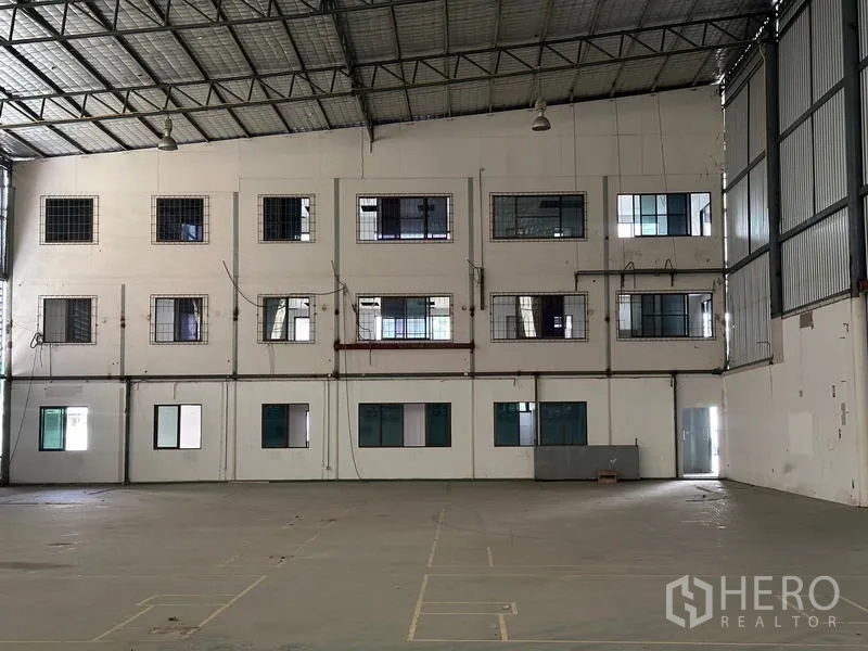 Warehouse for rent in Suan Luang, Bangkok - Close view of internal office façade with multiple windows inside the warehouse.
