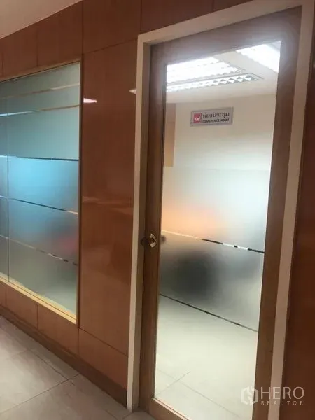 Office Space for rent in Sathon, Bangkok - Frosted glass door and glass partition along a corridor with wood wall panels inside an office.