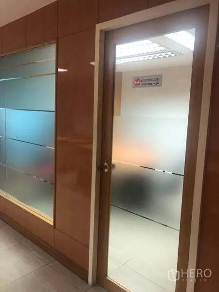 Office Space for rent in Sathon, Bangkok - Frosted glass door and glass partition along a corridor with wood wall panels inside an office.