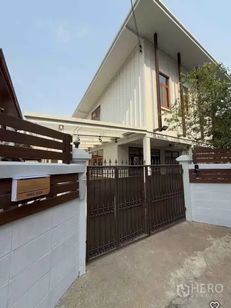 Detached House for rent in Khlong Toei, Bangkok - Front exterior of a two-storey detached house with high gable roof, wooden fence and wrought-iron gate.