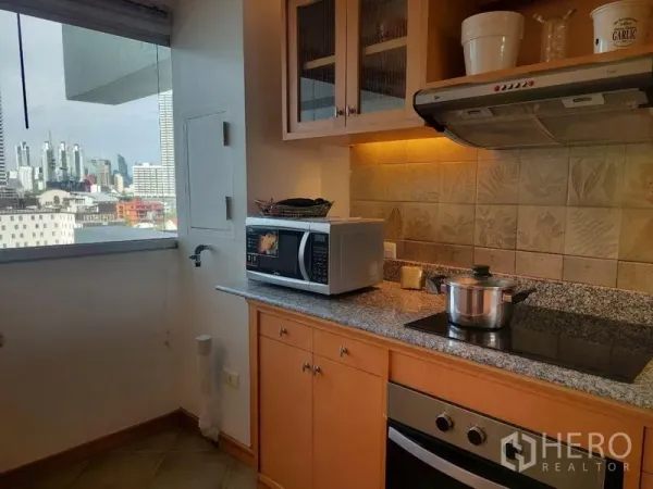 Apartment for rent - Compact kitchen with granite counter, electric cooktop, range hood and city-view window.