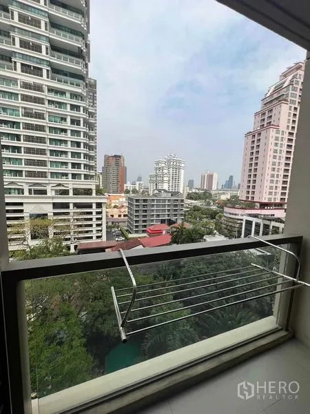 Condominium for rent or sale in Watthana, Bangkok - Balcony outlook to Sukhumvit skyline with mature trees and nearby high-rise buildings.